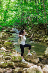 a woman with a backpack stands by the river in the woods on a rock hike travel walk