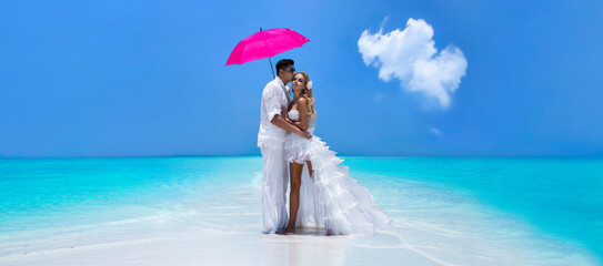 Summer love. Beautiful happy young couple in wedding clothes and pink umbrella is standing on a...