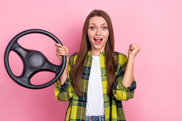 Portrait of young excited girl raise fist up hold steering wheel passed her exam driving wear yellow plaid jacket isolated on pink color background