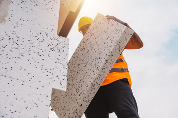 Mason applies glue to a thermal cladding on a construction site
