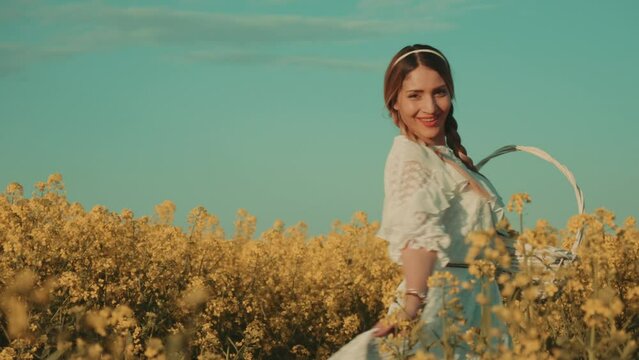 Beautiful young woman in white dress on yellow flower meadow in sunset