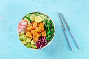 Salmon poke bowl with avocado, cucumbers, wakame, radish, and purple cabbage, a healthy Hawaiian dish with rice, overhead flat lay shot