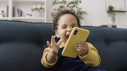 Extremely happy African American baby playing with parent's smartphone, childhood