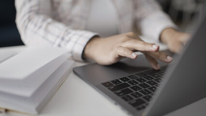 A woman typing on her laptop, taking notes, and communicating with customers in a close-up shot
