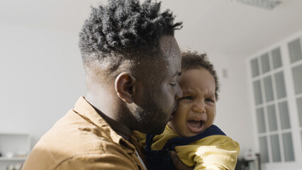 Single father tries to comfort his crying son, facing the difficulties of fatherhood