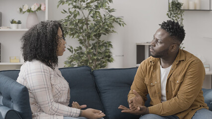 African American man talking with his wife on sofa, relationship crisis