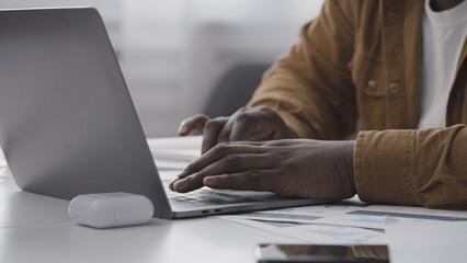 Close-up of African American man typing on laptop at home, remote work, freelance