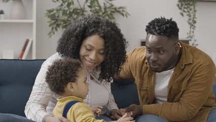 Cheerful African American parents admiring their cute baby-boy, happy parenthood