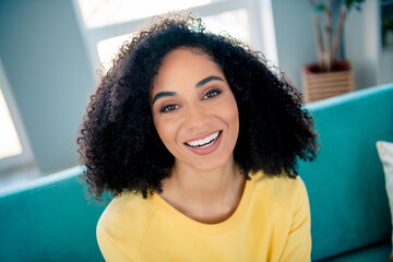 Photo of optimistic lovely girlish cute pretty woman with perming coiffure wear yellow long sleeve smiling laughing at home room indoors