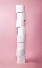 Tall toilet paper tower made of 8 stacked white tissue rolls isolated on pink. A lot of hygiene supply for bathroom or restroom stored by a hoarder household