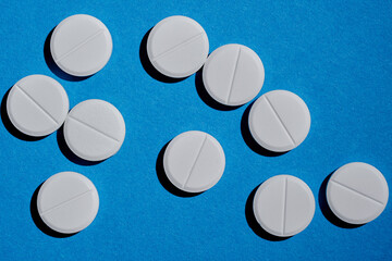 Medicine, drug, pharmacy and health care concept. Bunch of white tablets on blue background.