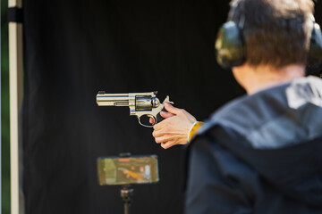 Shooting from a revolver in a shooting range outdoors. - obrazy, fototapety, plakaty