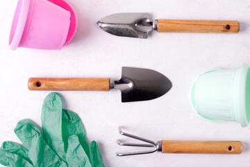 Gardening tools on white. Flat lay with rake, trowel, pots, and gloves. Top view	