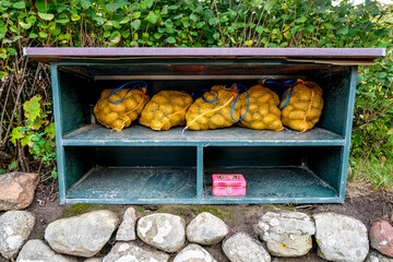 Kartoffeln unter einem Holzunterstand zur Selbstbedienung mit Kasse.