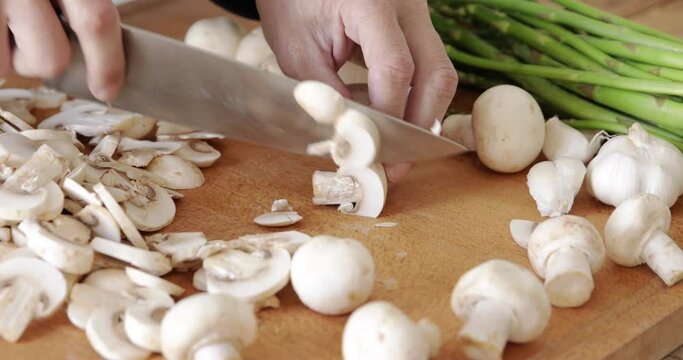 Champignon white button mushrooms chopped on wooden cutting board