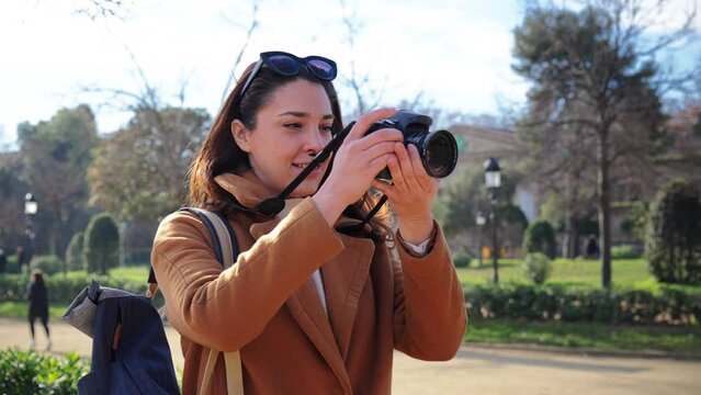 young female photographer smiling and shooting a artistic photo on a weekend travel activity. One caucasian hipster woman enjoying taking a pic with a retro professional camera on a vacation trip
