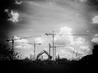 Monochromatic Symphony of Construction: Cranes and an Excavator Transforming the Urban Landscape