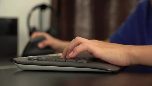 A boy works on a desktop computer - closeup on the hand on the keyboard