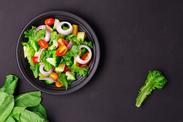 Healthy organic salad with fresh tomatoes, onions, spinach, and lettuce on a plate. Diet menu for weight loss. top view