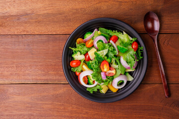 Healthy organic salad with fresh tomatoes, onions, spinach, and lettuce on a plate. Diet menu for weight loss. top view