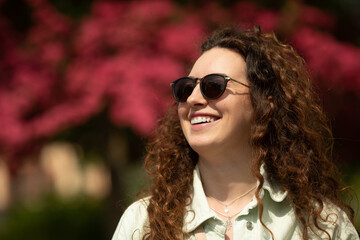 Portrait of a beautiful young woman with smile and sunglasses in the city. 