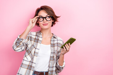 Portrait of thoughtful clever business lady wear plaid shirt smartphone looking interface new website options isolated on pink background - obrazy, fototapety, plakaty
