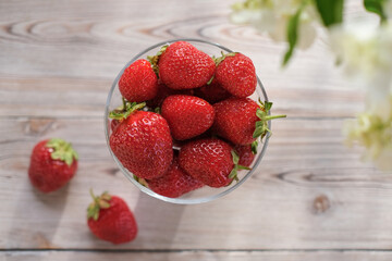 Top view of ripe strawberries in a glass bowl on a wooden table