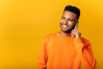 Indian man talking phone, calling to somebody, looking away with happy facial expression. Indoor studio shot isolated on orange background