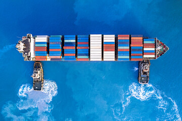 Tugboats assisting container cargo ship to harbor.