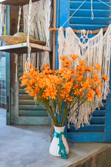 Zinnia angustifolia or narrowleaf zinnia in white vase against macrame and blue wooden doors