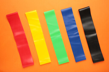 Multi-colored elastic bands for fitness on orange background.
