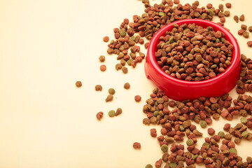 Pet food in red bowl on beige background.