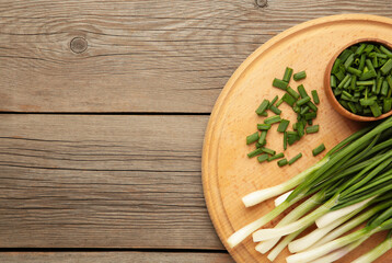 Fresh green onions on a cutting board on grey wooden background. Space for text