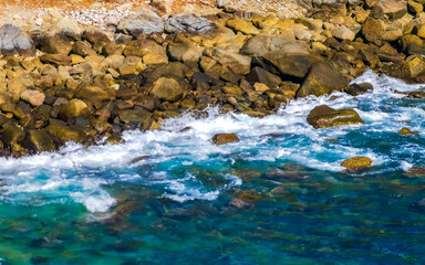 Surfer waves turquoise blue water rocks cliffs boulders Puerto Escondido.