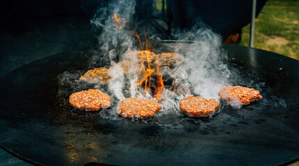 Preparing juicy beef hamburger patties . BBQ meat sizzling over hot flames.