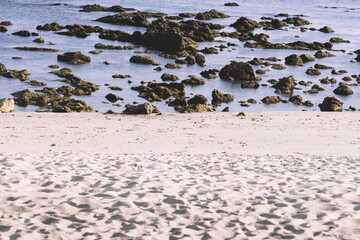 View of sandy beach at low tide revealing rocks on the ocean