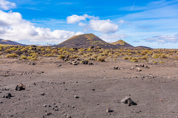 Sandy valley with hardened volcanic lava. In distance, the crater of the volcano. Canary mountains.