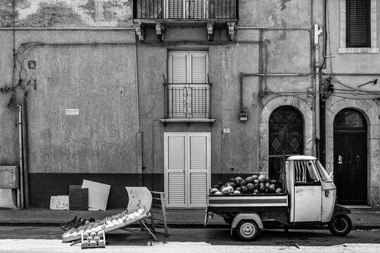 A Piaggio Ape with melons/fruitshop in Sicily, Italy.
Black and white.