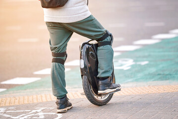 Man with knee pads on electric mono wheel waiting on crosswalk. Man on electric single wheel...