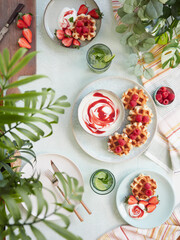 Top view of summer table with waffles served on plates with yogurt
