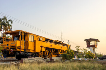 Fototapeta na wymiar Low angle view of yellow train stationary on grassy track near station.