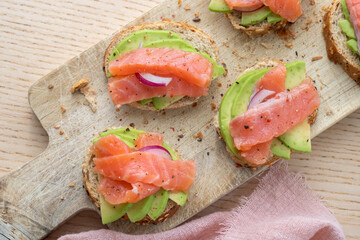 Toasts with avocado and smoked salmon on the wooden board