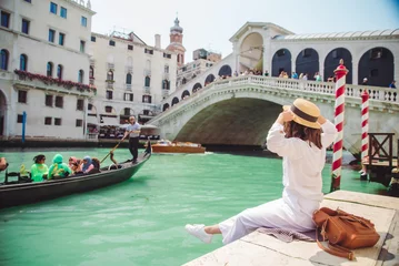 Fototapete Gondeln woman sitting near rialto bridge in venice italy looking at grand canal with gondolas