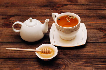 Liquid fresh linden honey in a plate with a wooden honey spoon and tea.