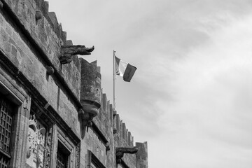 Black and white French flag open, blowing in the wind above The consulate of France in Rhodes located at Rue des Chevaliers street in the Old Town of the medieval city - obrazy, fototapety, plakaty
