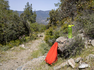 Red backpack and green water bottle on nature trail in Limassol National Forest Park, Cyprus