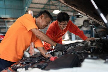 Asia mechanic man examining and maintenance to engine a vehicle car hood