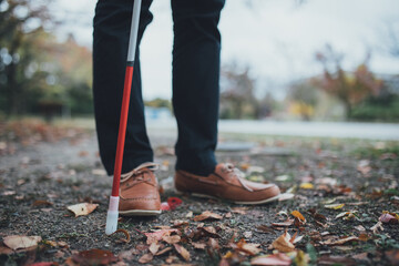 コートを着た視覚障害者の男性が白杖を使用している足元