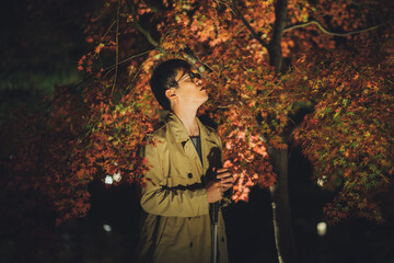 コートを着た視覚障害者の男性が夜の公園で自然を感じている
