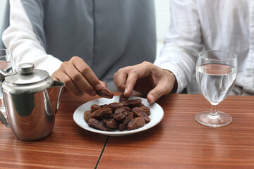 Ramadan Kareem background, close up of muslim couple hands picking up dates fruit during iftar or breakfasting.